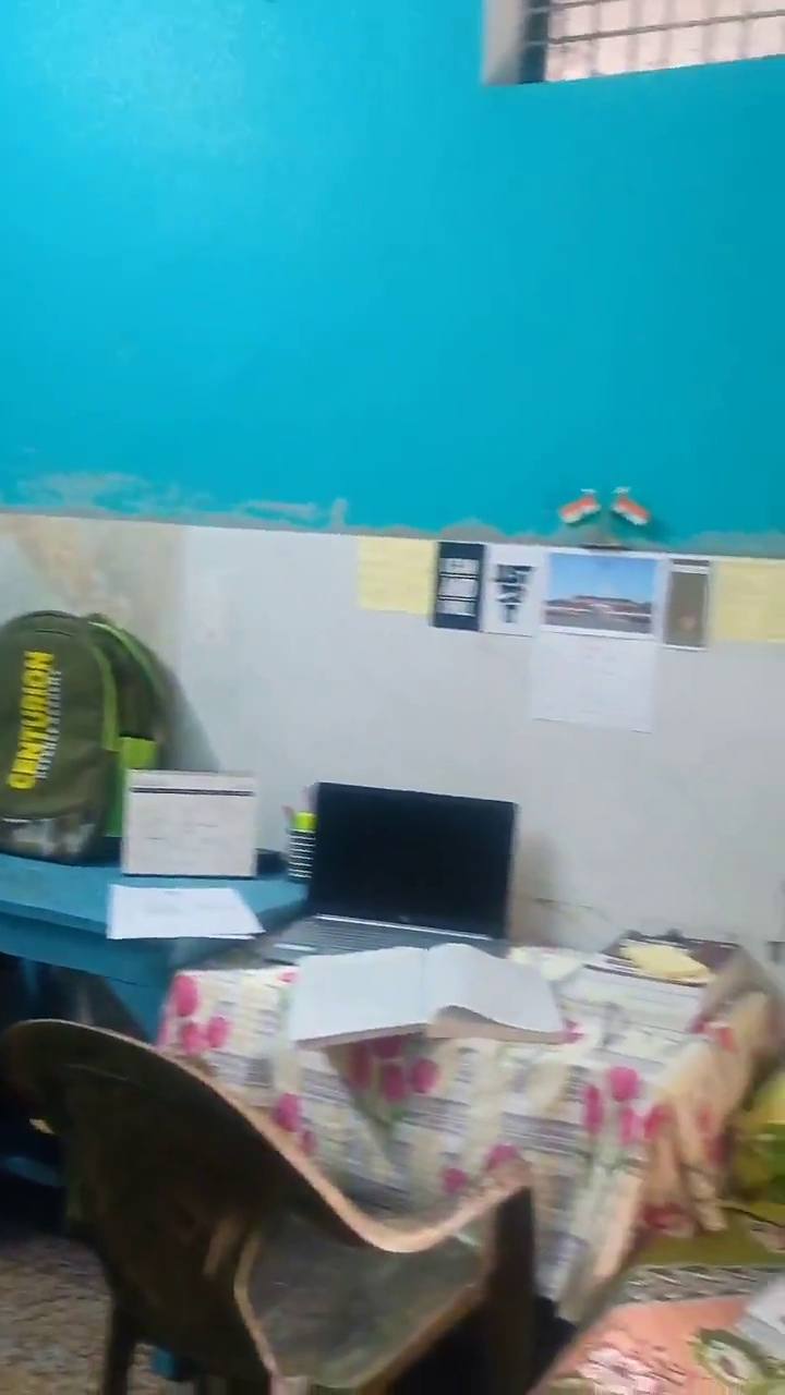 A study desk with a laptop, books and notes on the wall